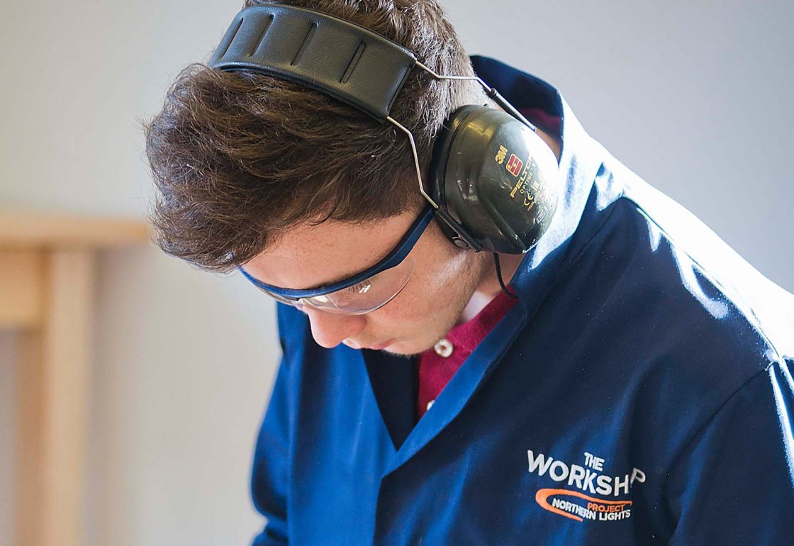 An image of a young male with protective eye glasses and earphones working for the Aberfeldy Community Workshop a charity supported by the Ellis Campbell Foundation, helping disadvantaged young people in Hampshire, London and Perthshire