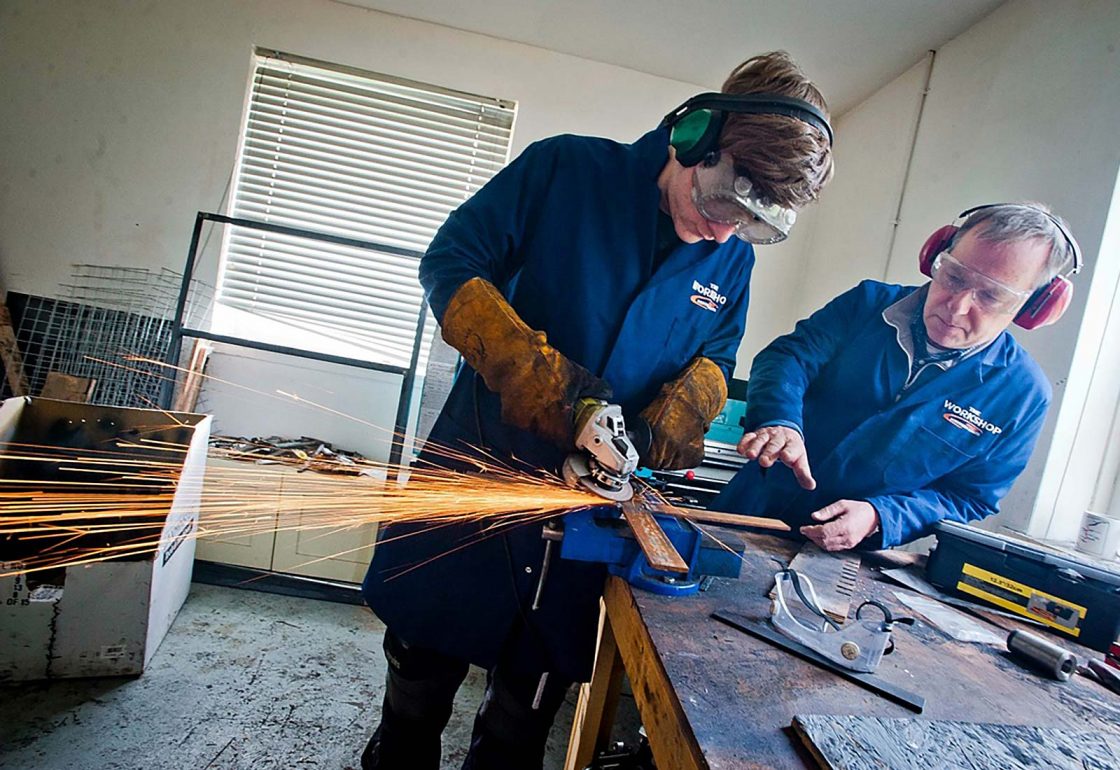 An image of a young male with teacher both with protective eye glasses and earphones working for the Aberfeldy Community Workshop a charity supported by the Ellis Campbell Foundation, helping disadvantaged young people in Hampshire, London and Perthshire