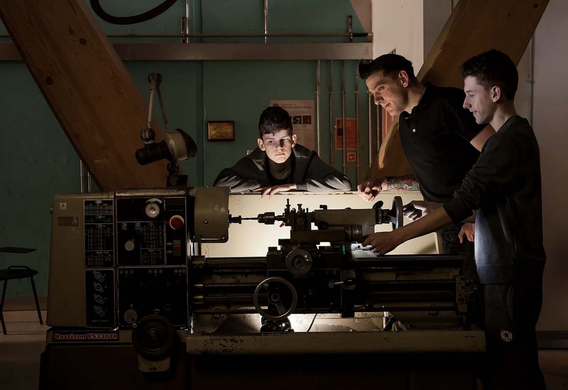 An image of young boys with a teacher using machinery and taking part in the Archway project, a motorcycle education and youth centre programme supported by the Ellis Campbell Foundation, helping disadvantaged young people in Hampshire, London and Perthshire