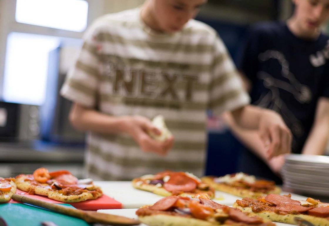 An image of young boys learning to cook and taking part in the Archway project, a motorcycle education and youth centre programme supported by the Ellis Campbell Foundation, helping disadvantaged young people in Hampshire, London and Perthshire