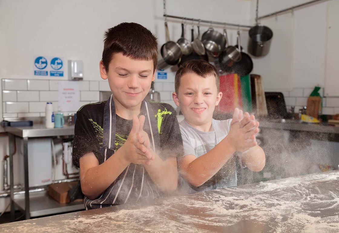 n image of young boys learning to cook and taking part in the Archway project, a motorcycle education and youth centre programme supported by the Ellis Campbell Foundation, helping disadvantaged young people in Hampshire, London and Perthshire