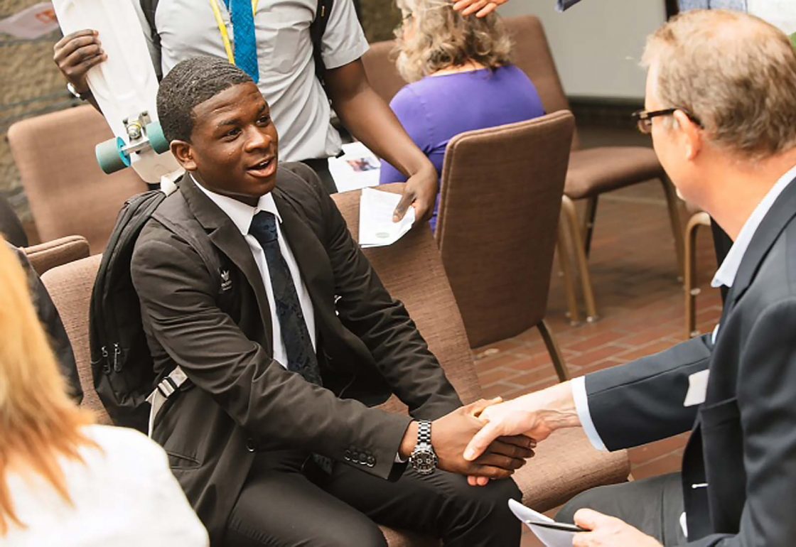 An image of a young black boy shaking hands representing the Envision Community Apprenticeship Programme, a charity supported by the Ellis Campbell Foundation, helping disadvantaged young people in Hampshire, London and Perthshire