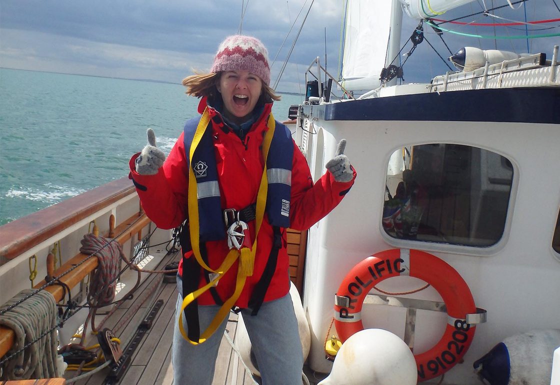 An image of a smiling female teenager enjoying sailing aboard the Prolific sailing boat part of Ocean Youth Trust South, a charity supported by the Ellis Campbell Foundation, helping disadvantaged young people in Hampshire, London and Perthshire