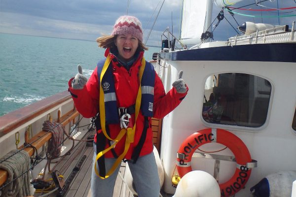 An image of a smiling female teenager enjoying sailing aboard the Prolific sailing boat part of Ocean Youth Trust South, a charity supported by the Ellis Campbell Foundation, helping disadvantaged young people in Hampshire, London and Perthshire