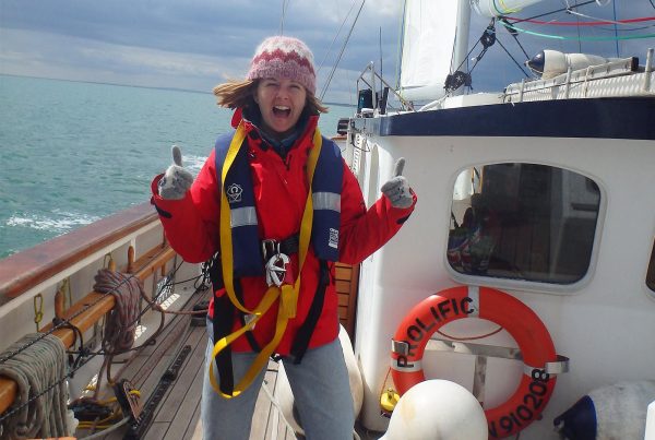 An image of a smiling female teenager enjoying sailing aboard the Prolific sailing boat part of Ocean Youth Trust South, a charity supported by the Ellis Campbell Foundation, helping disadvantaged young people in Hampshire, London and Perthshire