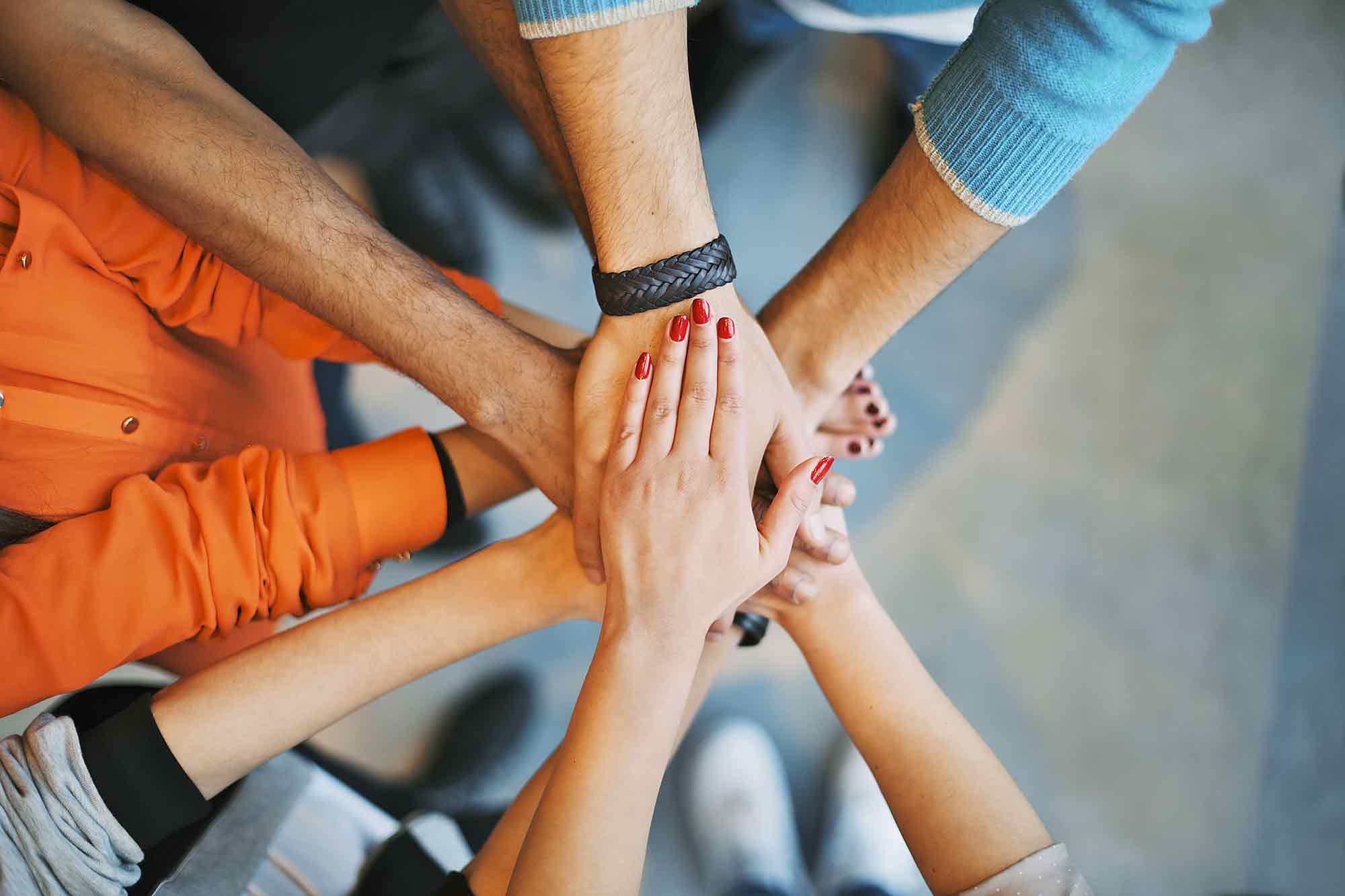 An image of hands of teenagers overlapping to portray helping used for the Ellis Campbell Foundation background image for grant applications, a charity giving grants in Hampshire, London and - Building Youth Power and Leadership