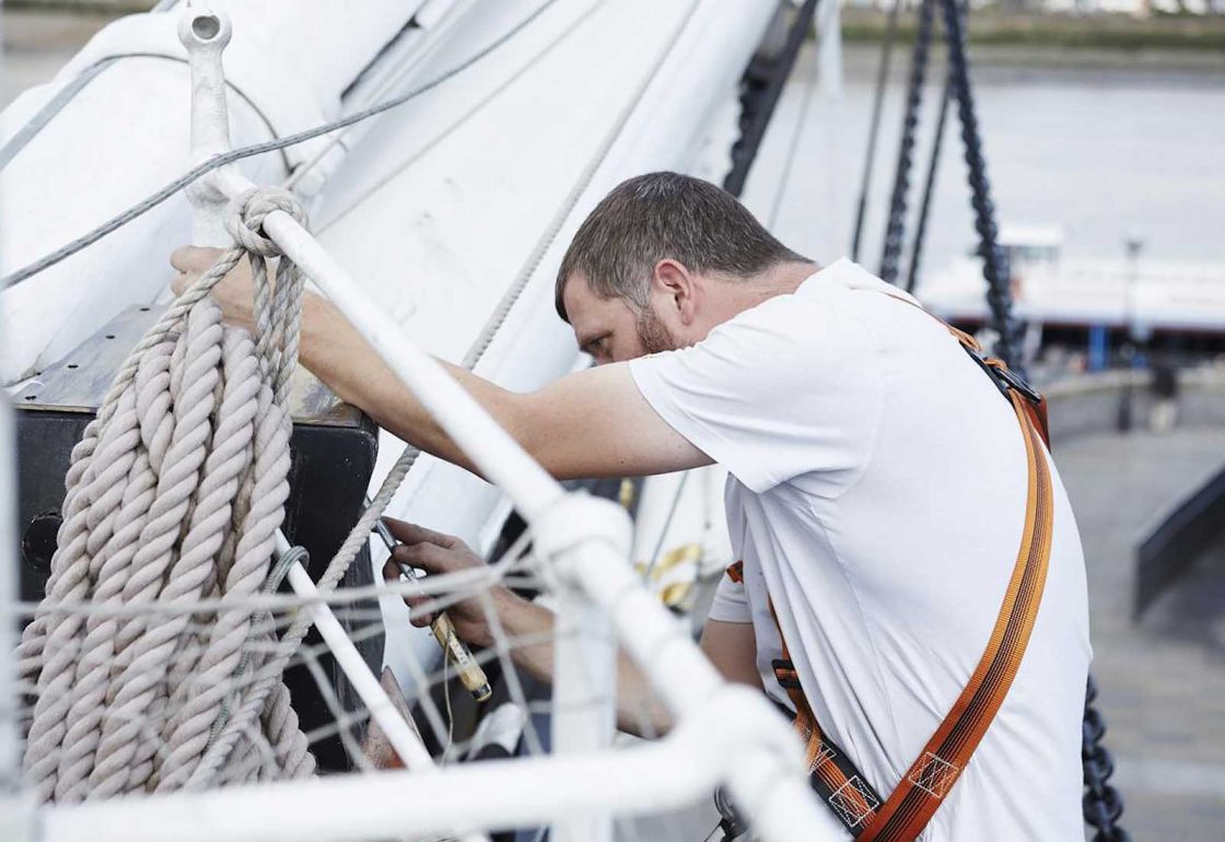 An image of a man fixing the rigging on the Cutty Sark representing the Lifeboats Conservation Project grant at the Royal Museum Greenwich made by the Ellis Campbell Foundation helping disadvantaged young people in Hampshire, London and Perthshire