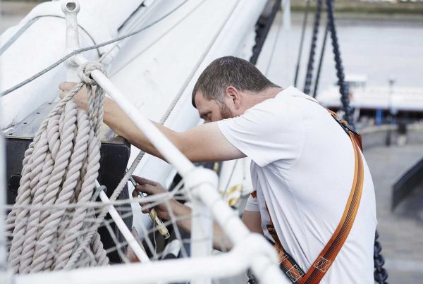 An image of a man fixing the rigging on the Cutty Sark representing the Lifeboats Conservation Project grant at the Royal Museum Greenwich made by the Ellis Campbell Foundation helping disadvantaged young people in Hampshire, London and Perthshire