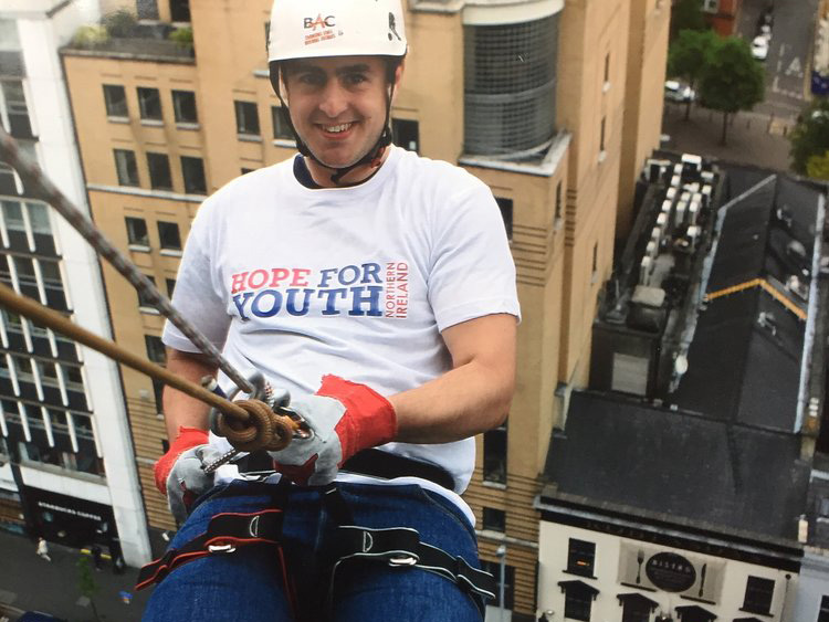 A colour image of Rob abseiling for Hope for Youth NI - a charity supported by The Ellis Campbell Foundation