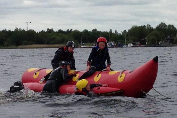 A colour image of a young people sat on and climbing aboard a red banana boat taking part in a Hope for Youth NI event supported by The Ellis Campbell Foundation
