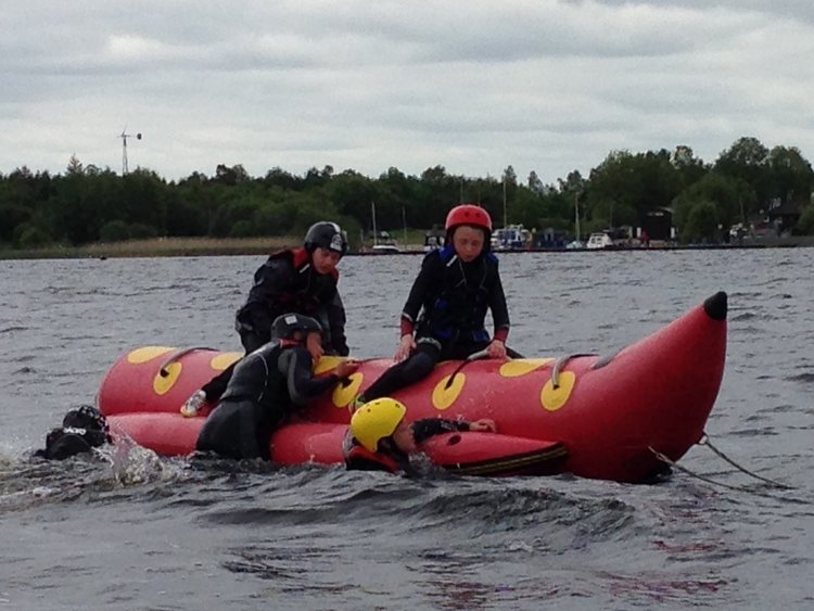 A colour image of a young people sat on and climbing aboard a red banana boat taking part in a Hope for Youth NI event supported by The Ellis Campbell Foundation