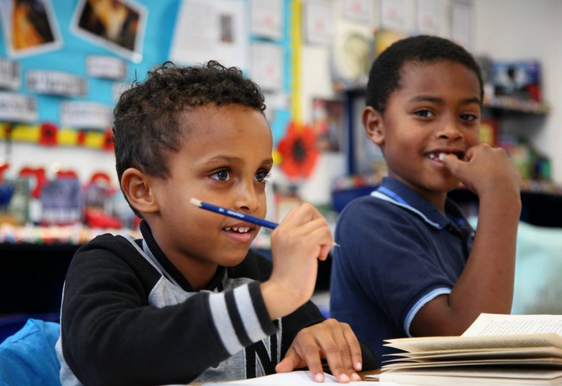 A colour image of 2 smiling children of different ethnicities - part of Young Sparks supported by the Kensington & Chelsea Foundation - The Ellis Campbell Foundation