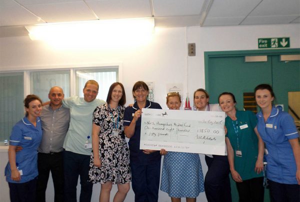 A colour image of Staff holding a cheque for £1850 raised as donations for the North Hampshire Medical Fund supported by The Ellis Campbell Foundation