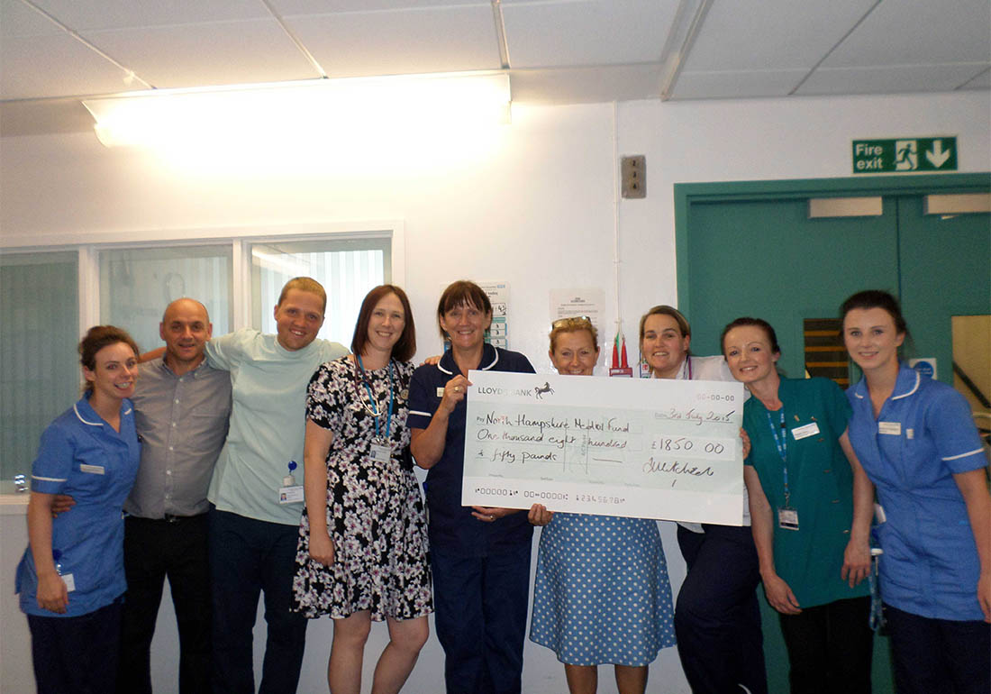 A colour image of Staff holding a cheque for £1850 raised as donations for the North Hampshire Medical Fund supported by The Ellis Campbell Foundation