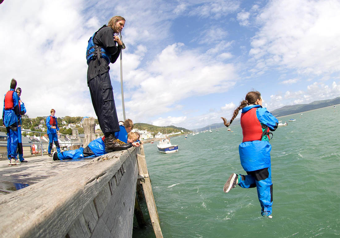 A colour image of a girl taking part in Outward Bound Snowdonia quay jumping - A charity supported by The Ellis Campbell Foundation