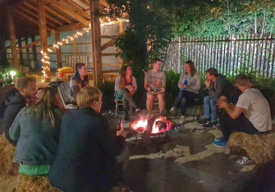 A colour image of a group of young people sat around a camp fire taking part inThe Oasis Farm Waterloo Urban Farm Initiative supported by the Ellis Campbell Foundation