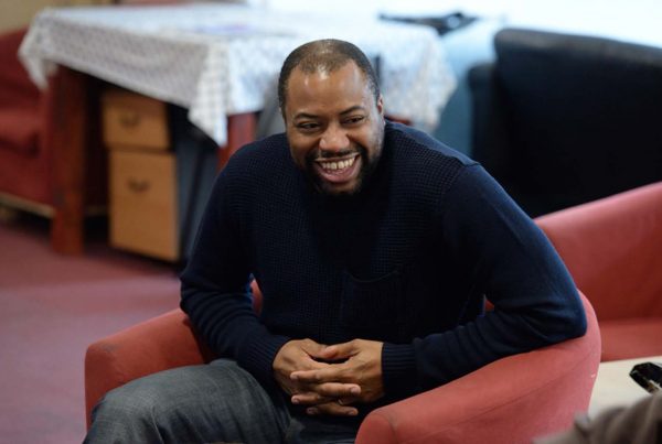 A colour image of a smiling black man in trousers and navy jumper taking part in the Khulisa Face It arts programme supported by the Ellis Campbell Foundation