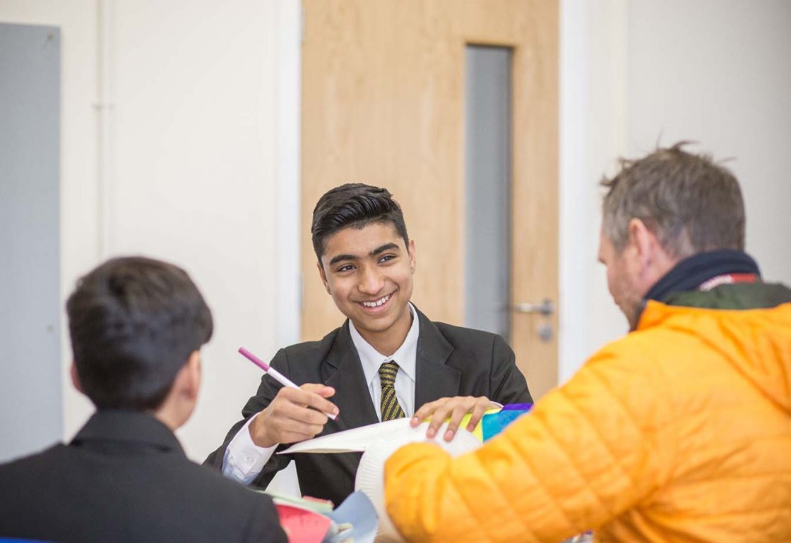 A colour image of a smiling mixed race boy, in blazer, shirt and tie taking part in the Khulisa Face It arts programme supported by the Ellis Campbell Foundation