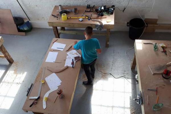 A colour image of a young male in a woodwork worshop taking part in the Oarsome Chance Maritime workshop - charity supported by the Ellis Campbell Foundation