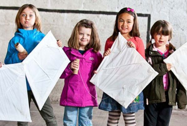 A colour image of six young girls standing in a line holding kites they have made as part of the Remake Scotland Craft Initiative supported by the Ellis Campbell Foundation