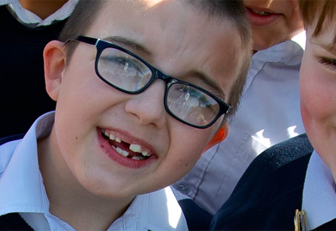 A colour picture of two smiling young boys in navy pullovers as part of the Achievement for All programme supported by The Ellis Campbell Foundation