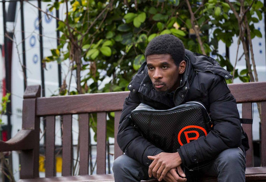 An image if a young black male sat on a wooden bench helped by Centrepoint - Helping the Homeless supported by The Ellis Campbell Foundation