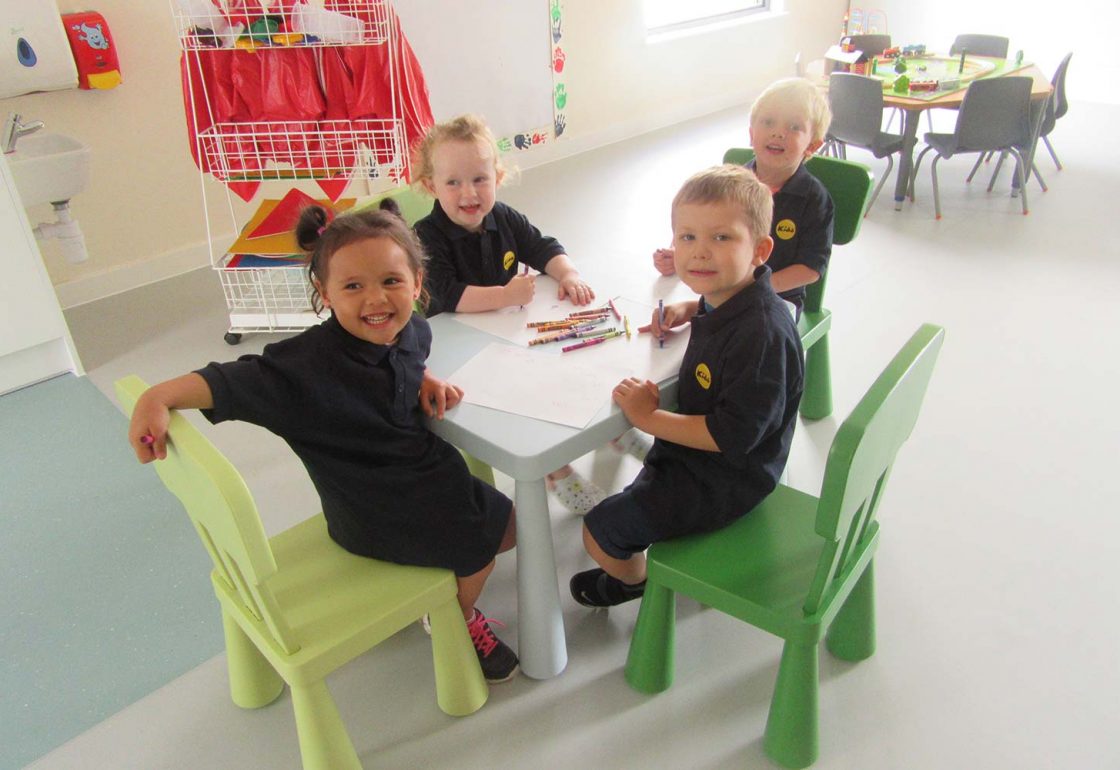 An image of 4 young children sat around a table drawing - part of the KIDS programme supported by The Ellis Campbell Foundation