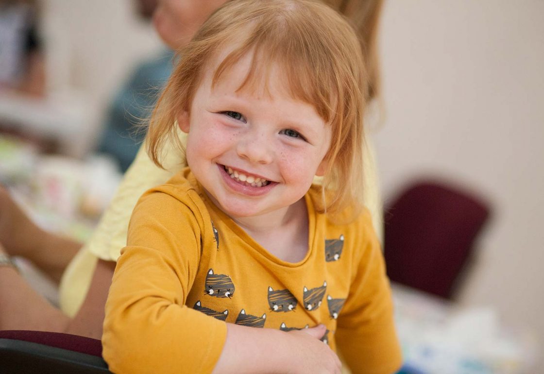 An image of a little girl with red hair smiling - supported by KIDS - The Ellis Campbell Foundation